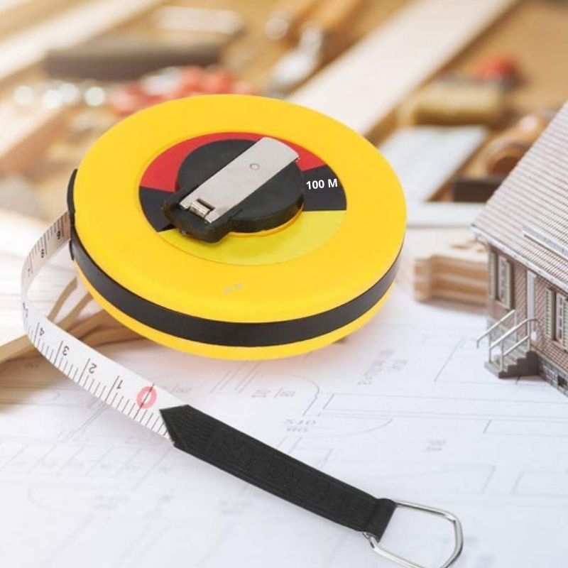 Mètre ruban souple 100m jaune posé sur plans d’architecte