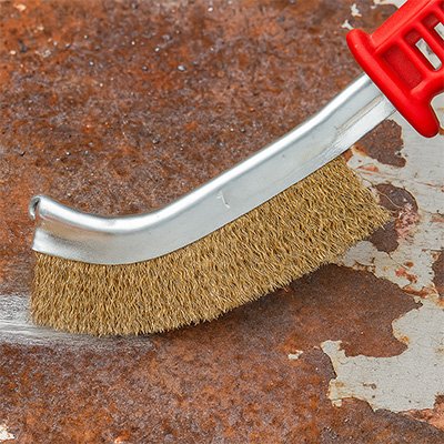Brosse metallique en train d’enlever la rouille  un plateau en acier