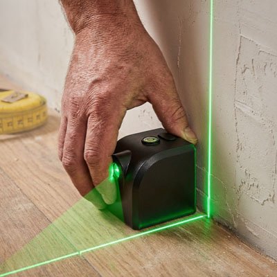  Laser niveau croix vert posé au sol contre un angle de mur