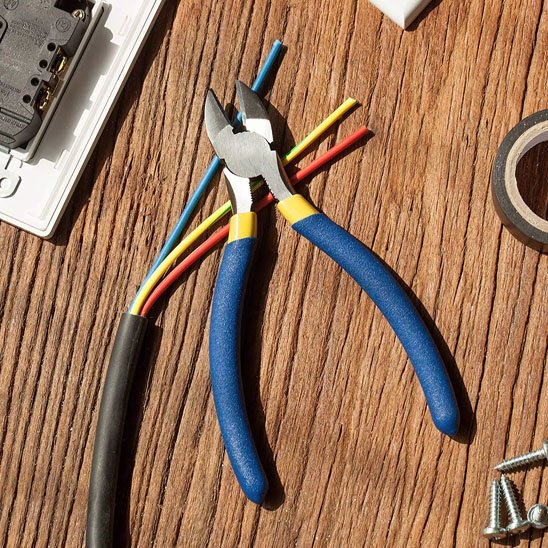 Pince coupante en usage dans atelier de maintenance électrique