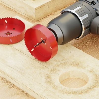 Scie cloche rouge fixée a une perceuse 