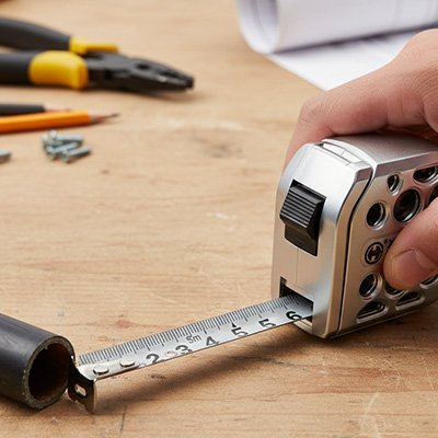 Mètre ruban compact mesurant un tube sur un établi de bricolage