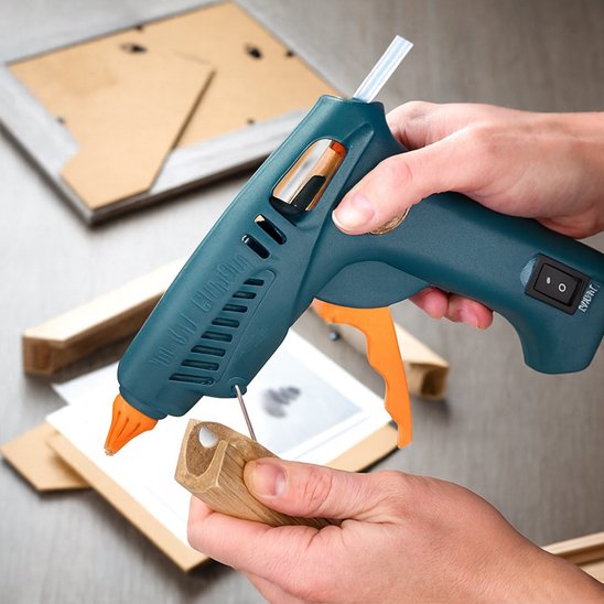 pistolet à colle avec gâchette orange utilisé pour coller du bois