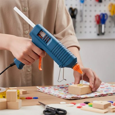 pistolet à colle bleu appliquant de la colle sur un bloc en bois