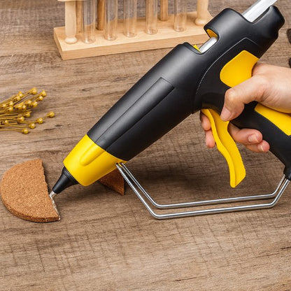 pistolet à colle noir et jaune posé sur un établi en bois