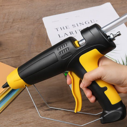 pistolet à colle noir et jaune tenu à la main sur un bureau